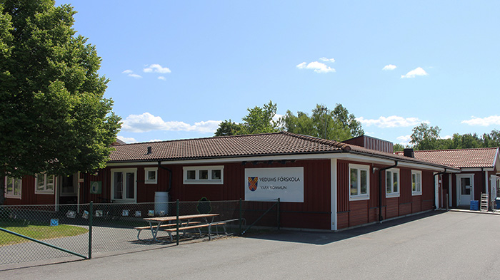 Röd låg skolbyggnad med skylten Vedum förskola mitt på.