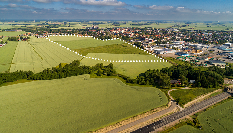 Flygfoto över en stad. Ett område inringat.